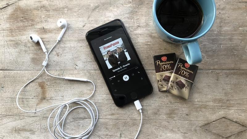 Smartphone with headphones, two chocolate bars and a cup of coffee.