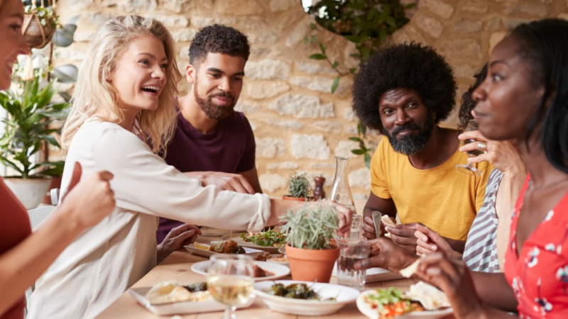 People sitting around a table dining and conversing together.