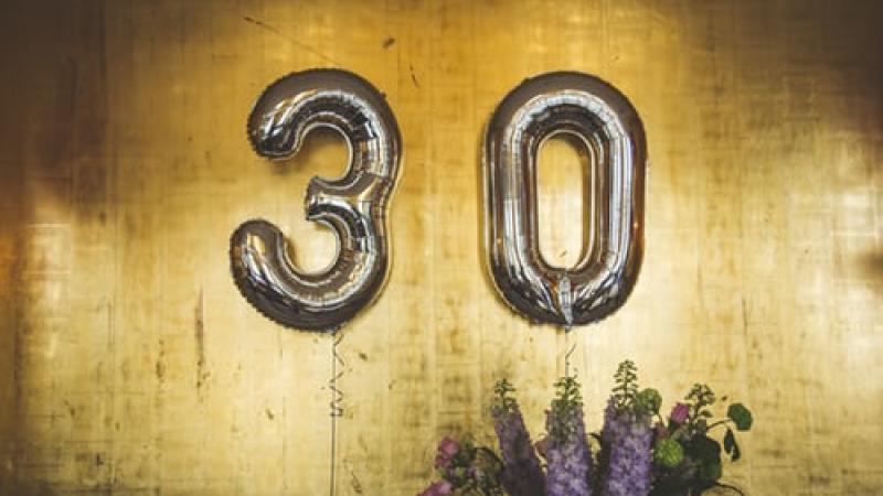 Silver number balloons that say 30 against a gold background.