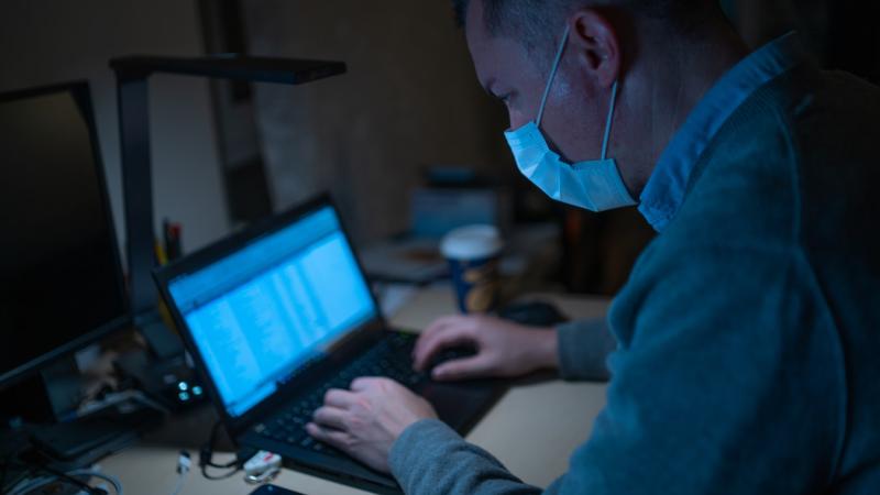 Man with a surgical mask on using laptop.
