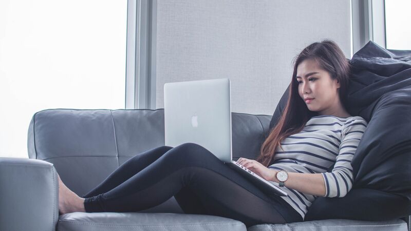Woman on a couch working on a laptop