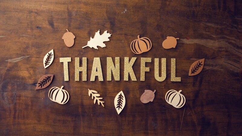 The word “Thankful” in gold lettering circled by fall leaves.