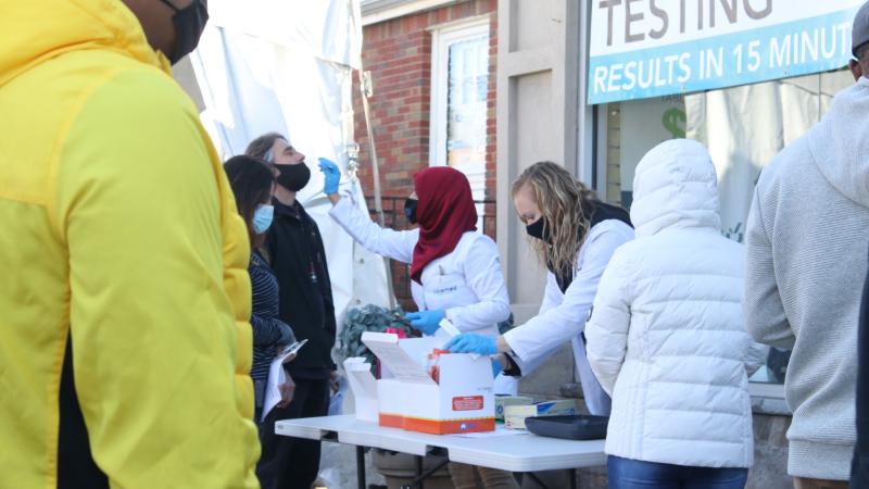 People line up in masks at a covid testing site.