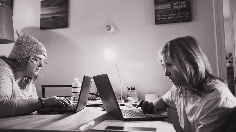 Two students using a laptop computers to access their learning at home.