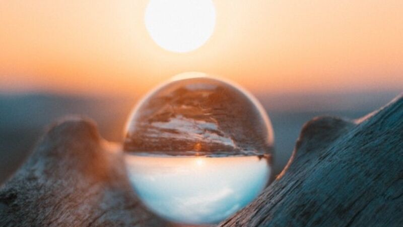 Sun rising behind a glass crystal ball.