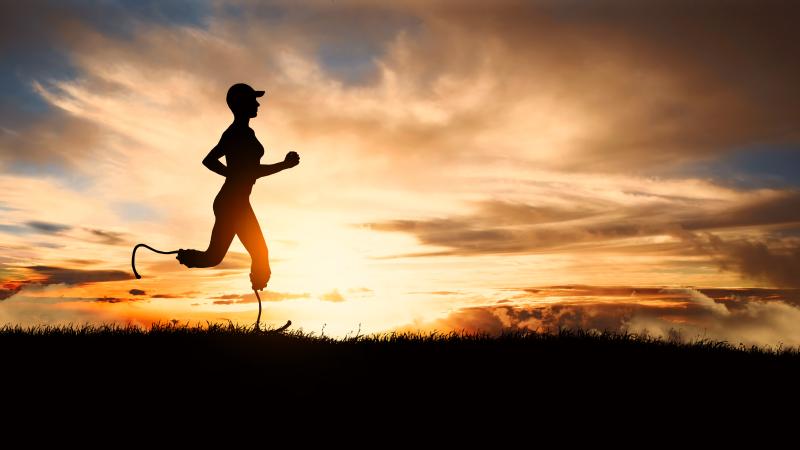 A lone runner with bladed lower legs shown in profile as a dark figure against a setting sun in a cloudy sky in the background.