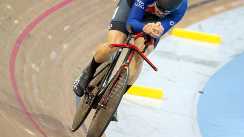 The blog author racing his track bike on a banked wooden track, hunched over in an aerodynamic position.