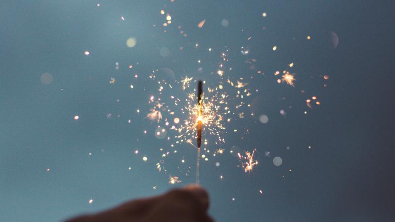 A photograph of a person holding lighted sparklers.