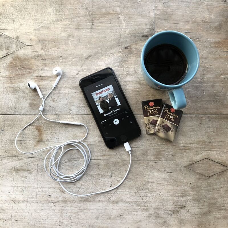 Smartphone with headphones, two chocolate bars and a cup of coffee.