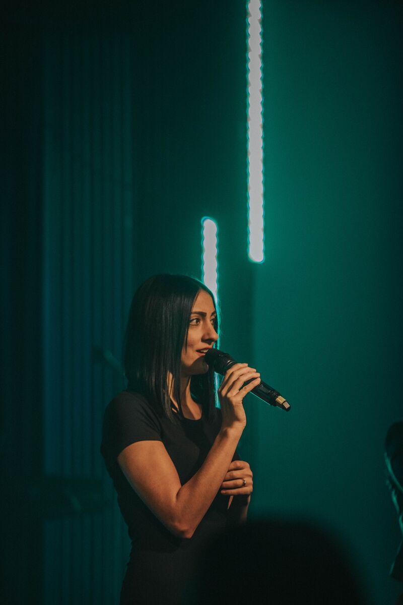 Woman standing using a microphone.