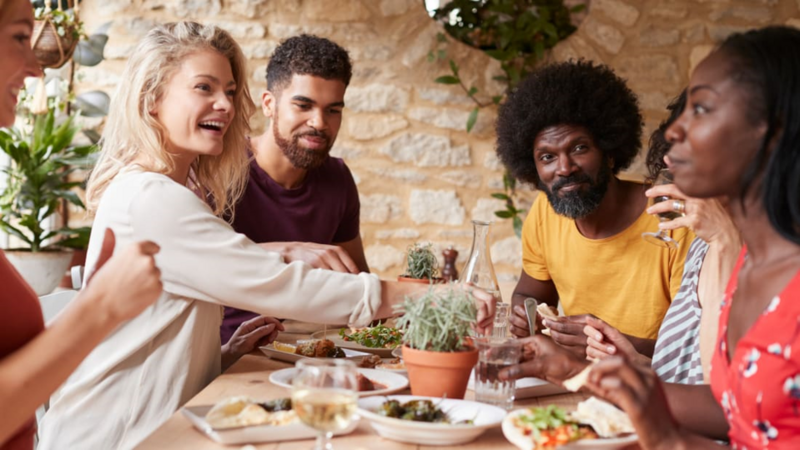 People sitting around a table dining and conversing together.