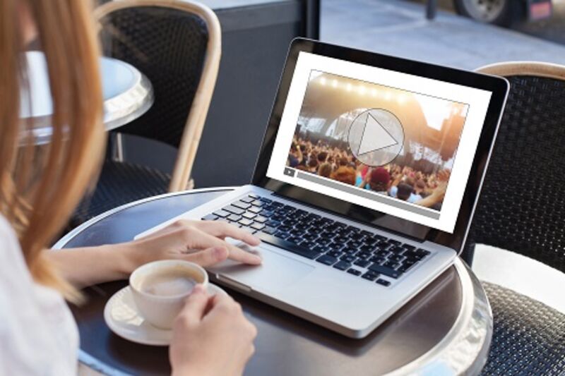 A woman watching a video on a laptop in a local coffee shop.