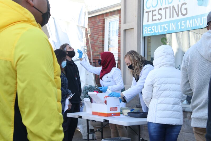 People line up in masks at a covid testing site.