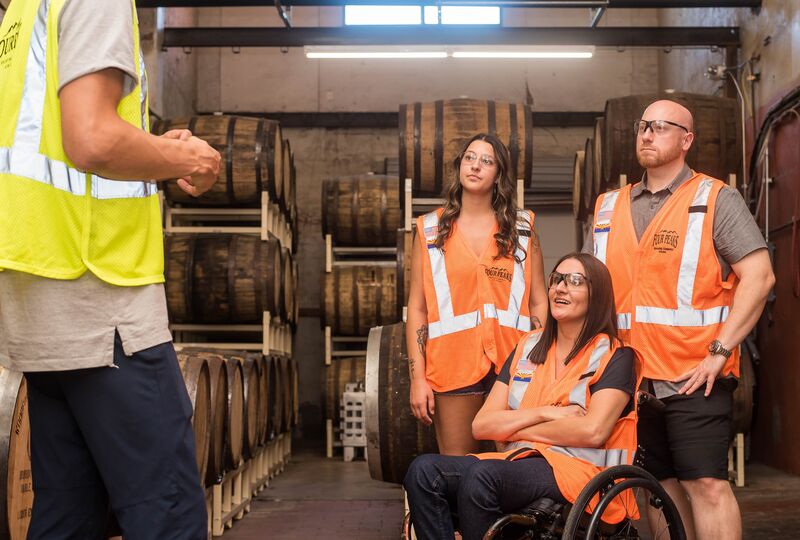 Workers in a brewery wearing safety vests having a discussion