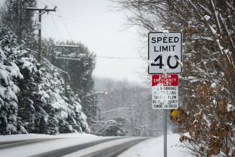 A snowy, tree-lined empty road