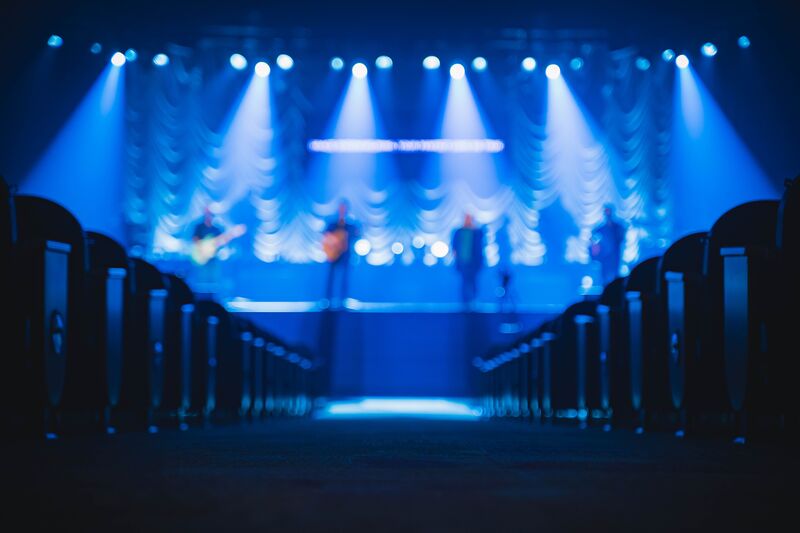 People on a stage playing instruments, empty seats.