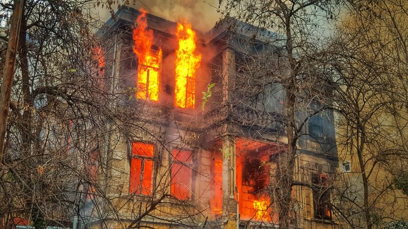 A burning building with flames coming out of the windows