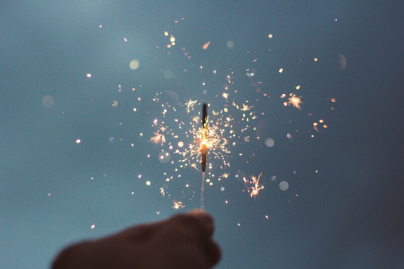 A photograph of a person holding lighted sparklers.