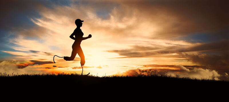 a silhouette of a woman running at sunset, the setting sun swirling around with the clouds in the sky. The runner uses a bladed prosthetic running leg for both lower legs.