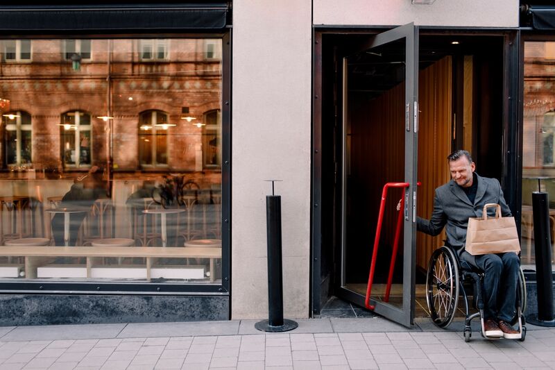 man in wheelchair opening the door to go outside