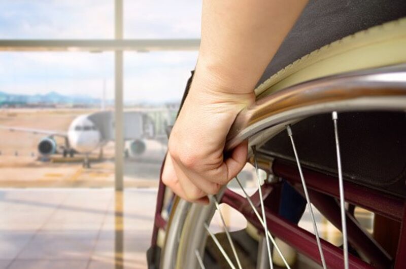 a wheelchair user sitting at the window, looking at a plane