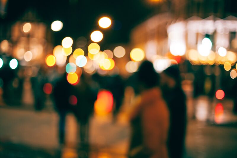 an out of focus picture of a group of people at night, blurred city lights in the background