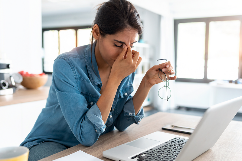 Stressed woman working from home on her laptop looking worried, tired and overwhelmed