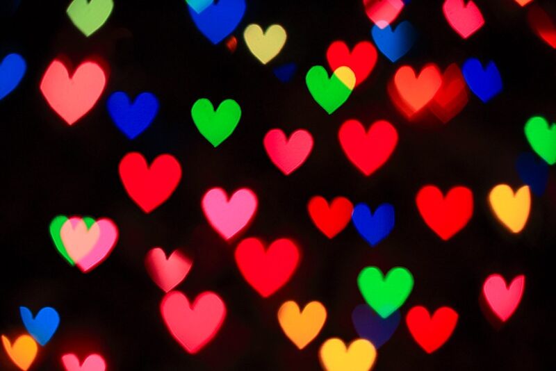 a bunch of colorful floating hearts on a black background