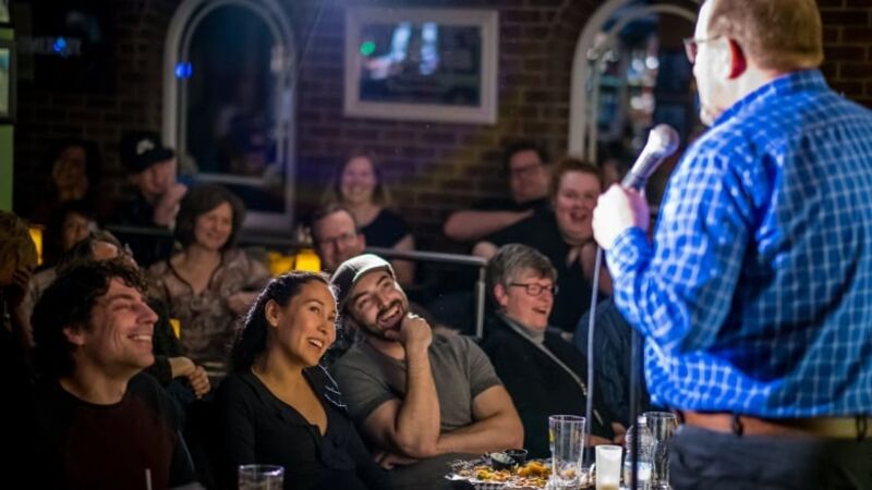 Stand-up white male comedian telling jokes to a laughing audience