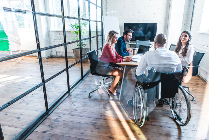 a group of four people are enjoying a business meeting, one member being a wheelchair user