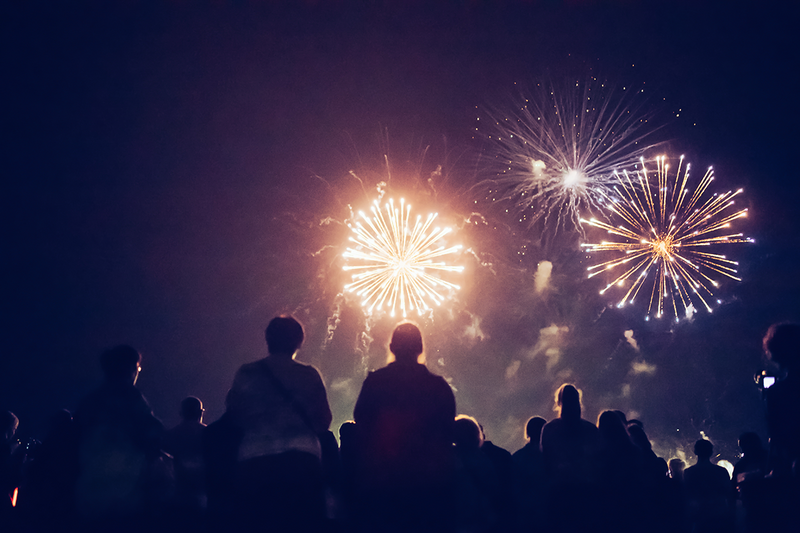 a crowd gathers to watch fireworks in night time