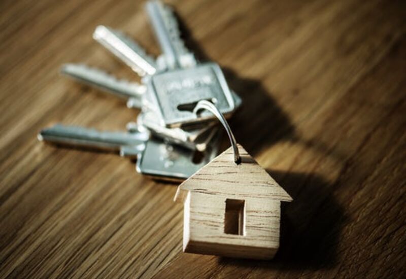 A set of keys on a keychain with a small wooden cutout of a house.