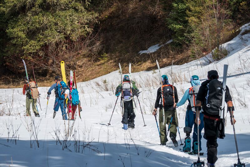 a group of people with various physical disabilities walking in the snow, carrying snow gear