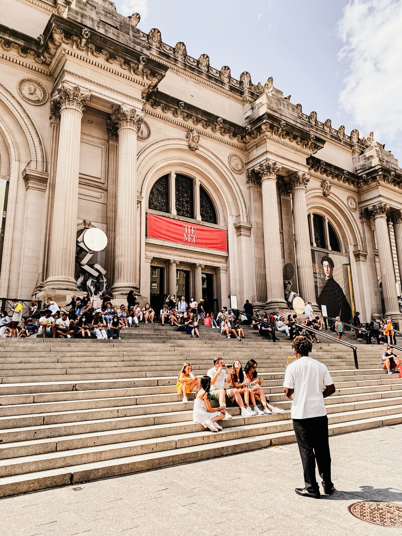 people sitting on the stairs outside the Metropolitan Museum of Art's entrance