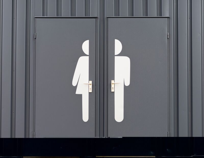 a pair of gray restroom doors, one labeled with a large pictogram of a woman and the other of a man