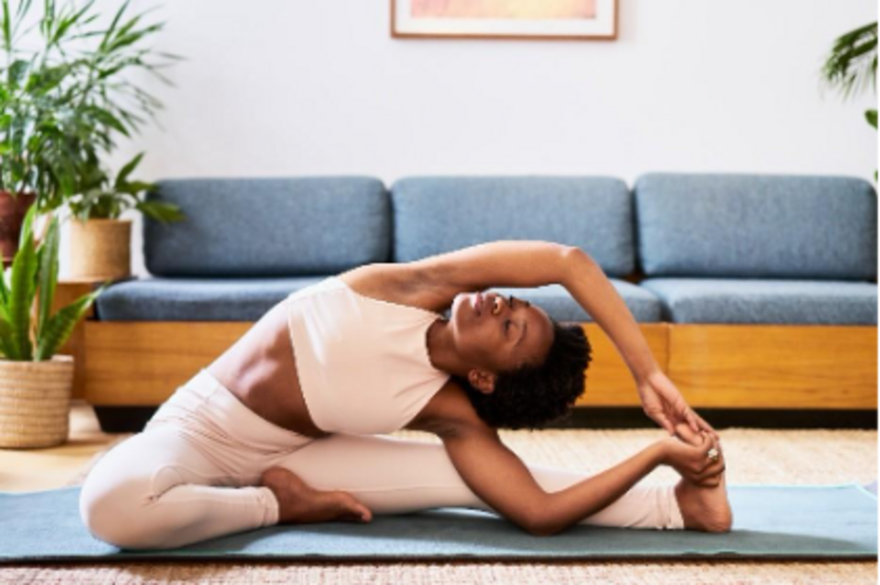 a black woman sitting on a yoga mat stretching 