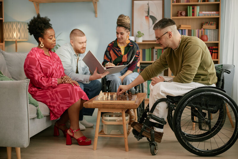 Group of people around a table playing chess.