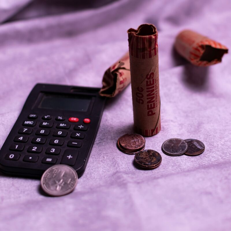 A calculator next to some pennies and coins on a table. 