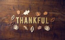 The word “Thankful” in gold lettering circled by fall leaves.