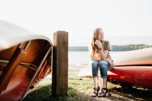 Woman sitting near canoes by lake