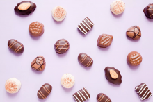 Assorted chocolate candies on a purple background.