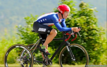 Ryan Boyle speeds on his trike in Team USA colors through a flat section of countryside meadow.