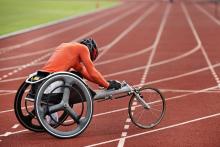 wheelchair athlete in orange jersey in a racing chair on running track