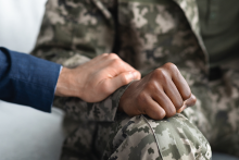 a white hand holds an African American soldier's hand