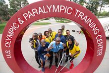 a group of 10 individuals from Uganda posing in the middle of the opening of a circular sculpture with the U.S. Olympic and Paralympic Training Center insignia