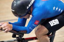 a close up profile of Chris Murphy racing his bike in France, wearing a smooth black helmet and a Team USA speed suit
