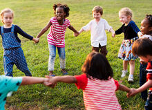 kids having a fun time together holding hands outside on the grass
