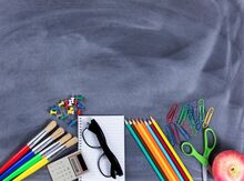 background of a chalkboard with school supplies scattered across it