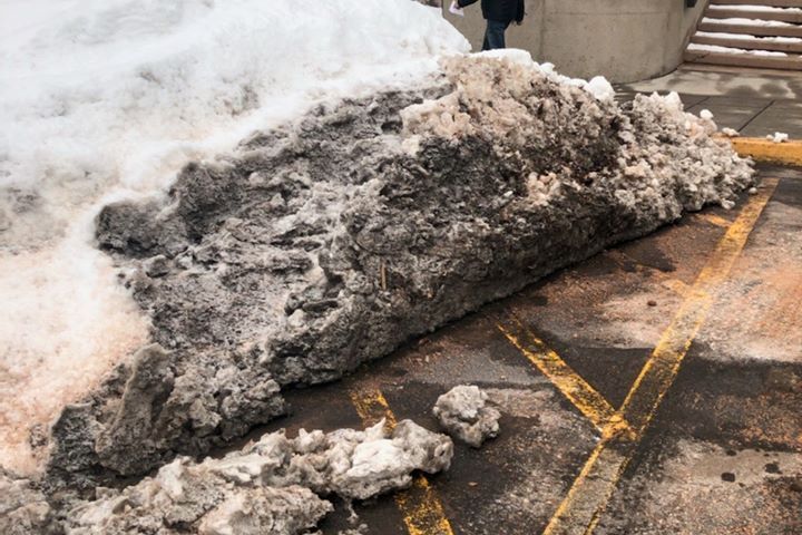 Huge pile of snow in an accessible parking space and access isle.