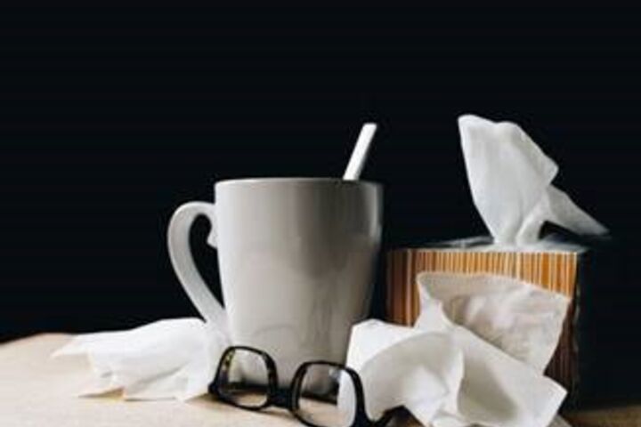 White ceramic mug, tissues, and glasses on a table. 